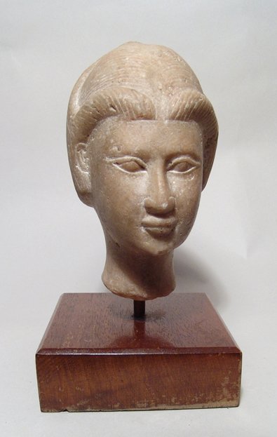 A Near Eastern alabaster head of a woman or goddess: A Near Eastern alabaster head of a woman or goddess, c. 1st Millennium BC, with Egyptianizing features, her hair stylized and pulled upward into a pointed crest, parted and pulled to the sides in fron