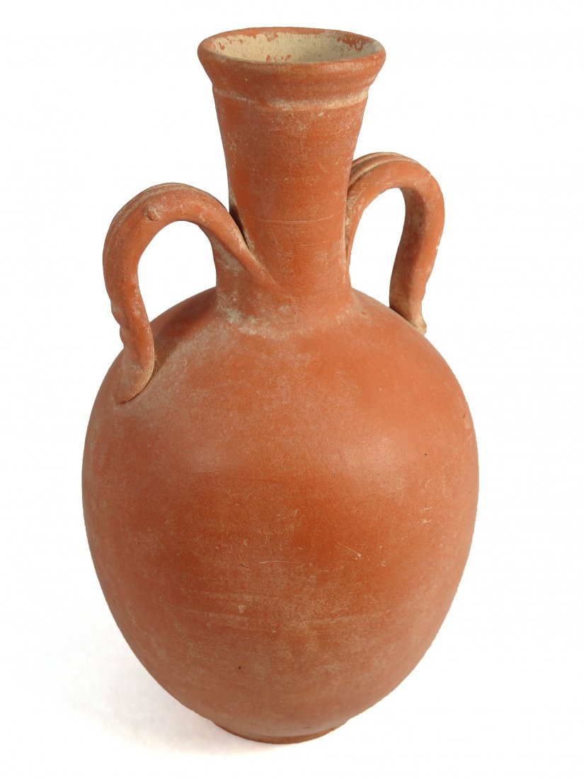 A Roman orange-ware bottle, North Africa: A Roman orange-ware bottle, North Africa, c. 3rd - 4th Century AD, the body ovoid and neck tapering to a flaring mouth with flat rim, a loop handle to either side. Both handles are nicely scored with 