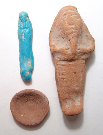 A pair of Egyptian ushabtis and an offering dish: A pair of Egyptian ushabtis and an offering dish. The first ushabti is a pale-blue Late Period type, c. 64 - 30 BC, with good color. H: 3 ¼ in (8.2cm). The second is a terracotta ushabti from the Hol
