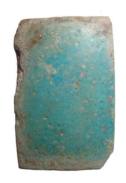 Egyptian light blue-green faience tile: An Egyptian light blue-green faience tile, 3rd Dynasty, c. 2686 - 2613 BC, of convex rectangular form and pierced at the back just beneath a raised rectangular lug. 2 3/8 in x 1 ½ in (5.8 x 3.8 cm).