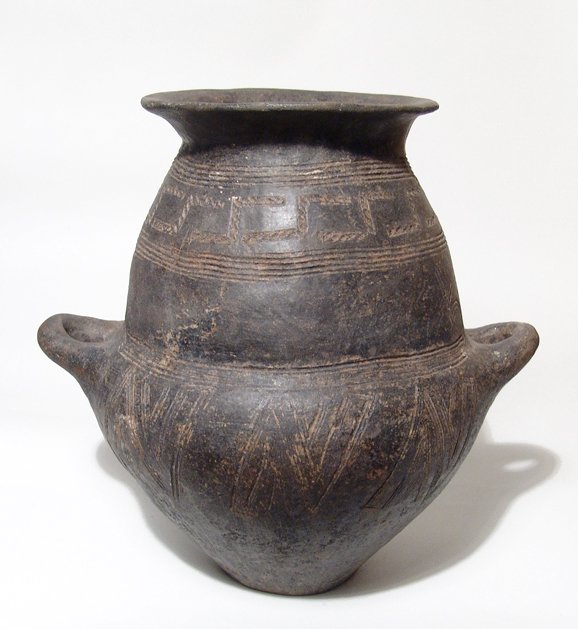 Etruscan / Villanovan Biconical Impasto Urn: An Etruscan / Villanovan Biconical Impasto Urn, c. 8th Century BC, of burnished black-ware with two upturned handles, the body with impressed geometric decoration and parallel grooves. A large and att