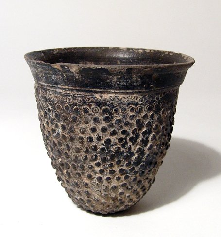 An attractive Greek Black-ware cup: An attractive Greek Black-ware cup, c. 4th - 3rd Century BC, the outside of the body textured with raised pellets, the circular base flat and the mouth lightly flared with parallel grooves at the base