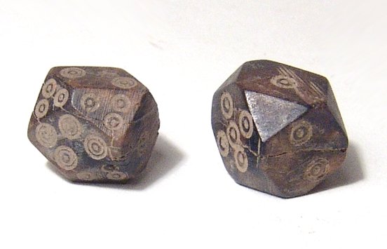 A pair of Roman bone dice with faceted edges: A pair of Roman bone dice with faceted edges, c. 1st - 4th Century AD, darkly colored, the main faces are properly numbered 1 through 6, the faceted edges of one with three circles on each, the other 