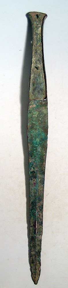 A heavy Near Eastern bronze dagger or short sword: A heavy Near Eastern bronze dagger or short sword, c. 1200 – 800 BC. This finely made weapon is 16-1/4 in long and is cast in one piece. The tapered blade has a thick center rib and the hilt is flan