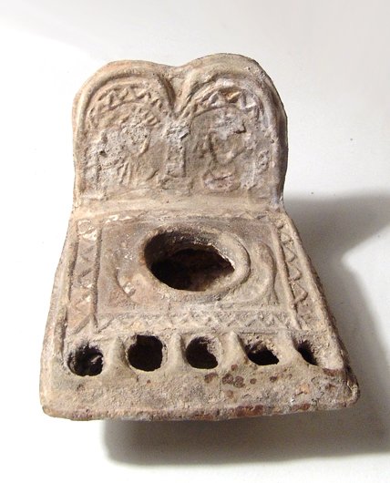 A choice Byzantine lamp with 5 wick-holes: A choice Byzantine lamp with 5 wick-holes, Holy Land, c. 7th- 8th Century AD, the body square in shape, the central fill-hole flanked by floral elements, all within a raised geometric border, five wic