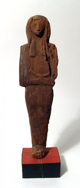 An Egyptian wood ushabti: An Egyptian wood ushabti, Late New Kingdom, 1292 - 1075 BC, depicted mummiform, wearing tripartite headdress. arms folded across abdomen and holding an uncertain object. Quite serene and a more unusua