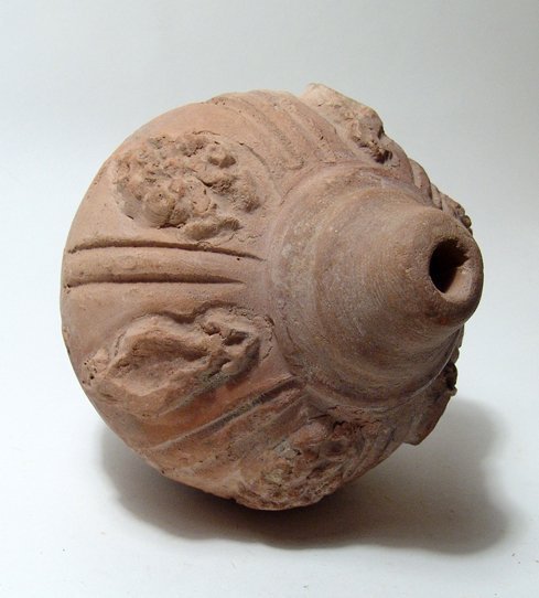 A choice Islamic period ceramic grenade, Holy Land: A choice Islamic period ceramic grenade, Holy Land, c. 6th - 9th Century AD, the shoulder with floral elements in high relief separated by parallel vertical grooves between each. Domed top with openin