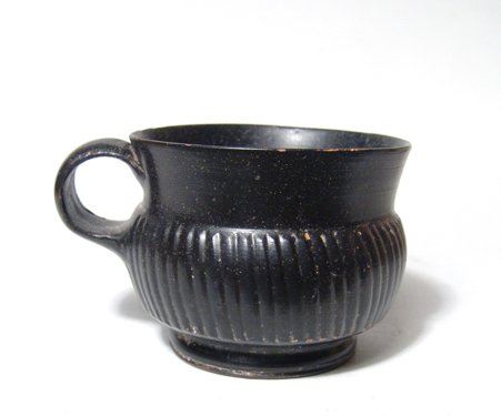 A nice Campanian Greek black-ware olpe: A nice Campanian Greek black-ware olpe, Magnia Graecia, c. 4th Century BC, the body nicely ribbed in imitation on metal-ware. H: 2 ¼ in (5.7 cm). Repaired chip to rim, nice surfaces. Ex Orange County