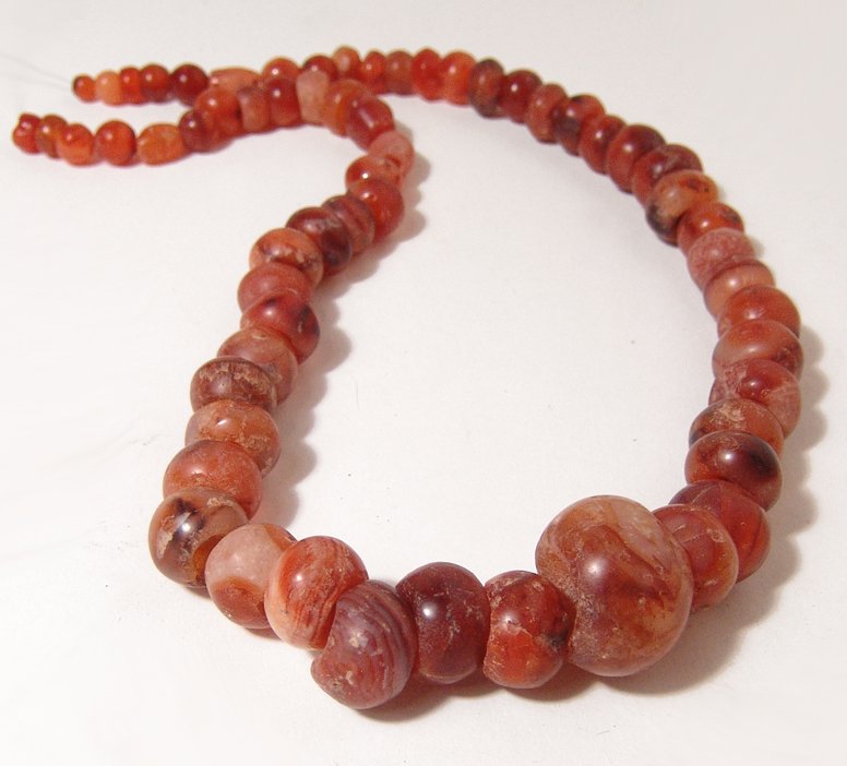 A nice strand of graduated carnelian beads, Holy Land: A nice strand of graduated carnelian beads, Holy Land, c. 1st Millennium BC, all with good color with the largest serving as a pendant. Length about 15 ½ in (39.6 cm) (53.8 cm). Ex Los Angeles privat
