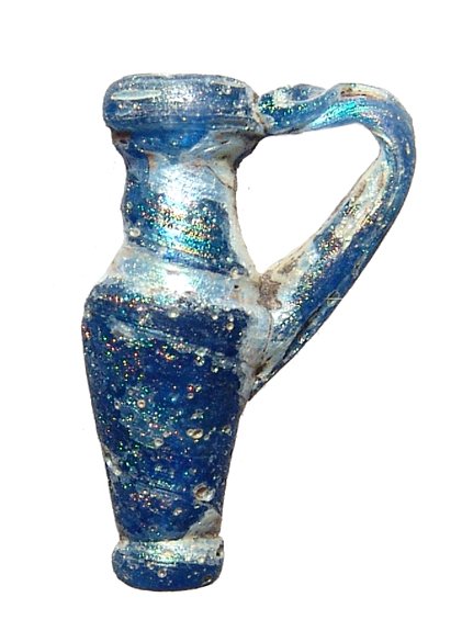 Late Roman - Byzantine blue glass pendant juglet: A nice Late Roman - Byzantine blue glass pendant juglet, c. 4th - 7th Century AD, with loop handle, the body with vibrant iridescence and decorated with horizontal white bands. L: 3 cm. Intact. Ex Los