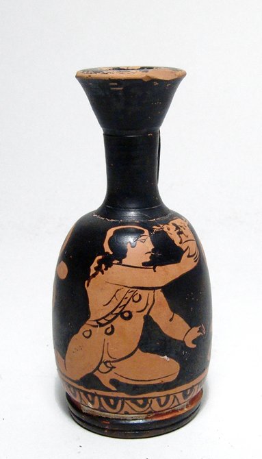 An Apulian Greek Red-Figure Lekythos: An Apulian Greek Red-Figure Lekythos depicting a kneeling youth, Magnia Graecia, c. 4th Century BC, he is nude except for drapery over his right shoulder and he wears anklets, he holds a large skyphos