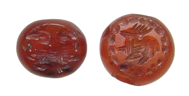 A pair of Sasanian carnelian stamp seals: A pair of Sasanian carnelian stamp seals, c. 3rd - 7th Century AD, both with handles in classic domed form and holed through sides for suspension. On the base of the first is a horned antelope facing 