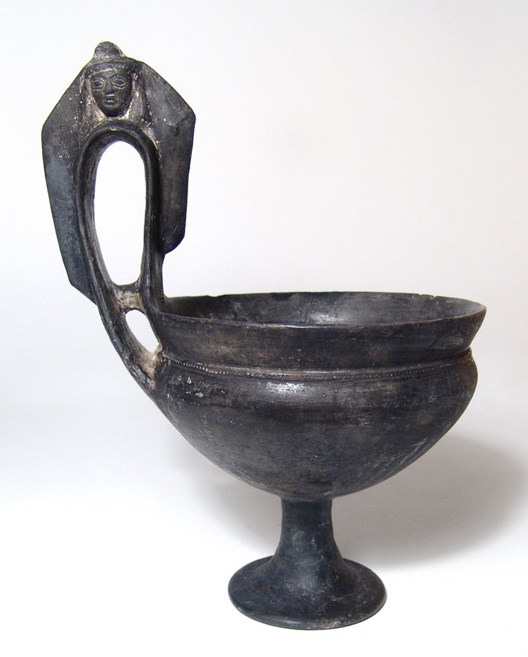 An Etruscan Bucchero pesante Kyathos: An Etruscan Bucchero pesante Kyathos, c. 560 - 540 BC, with tall stemmed foot, the base of the bowl beautifully tapered with rouletting around the base of the flared rim. The handle with tall vertical