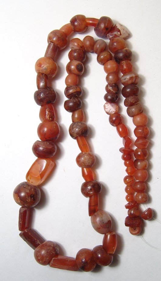 A large strand of multi-sized carnelian beads: A large strand of multi-sized carnelian beads, Holy Land, c. 1st Millennium BC, 74 in total, and include graduated round beads, roughly tubular types with tapered ends or faceted sides and a couple di