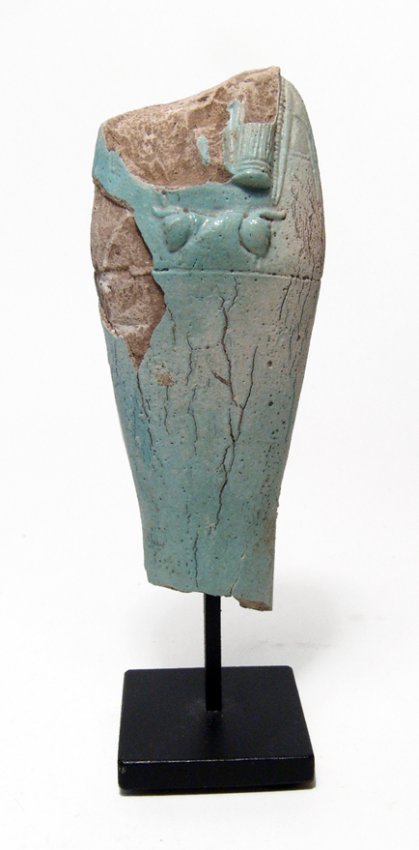 A pale blue Egyptian faience ushabti: A pale blue Egyptian faience ushabti, Late Period, c. 664 - 343 BC, mummiform, with arms folded across chest, hands holding pick and hoe, basket at shoulder and vertical plinth at back. H: 4 3/8 in (1
