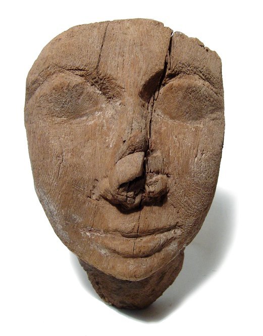 An Egyptian wooden mummy 'mask', Late Period: An Egyptian wooden mummy 'mask', Late Period, c. 64 - 30 BC, with nicely carved features and with a tab to help fasten it to the front of the sarcophagus. H: 7 1/8 in (18.2cm), W: 4 3/5 in (11.7cm). S