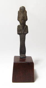 An Egyptian bronze figure of Osiris: An Egyptian bronze figure of Osiris, Late Period, c. 664 - 332 BC, mummiform, wearing atef crown with uraeus and false beard, arms folded at chest, hands holding a crook and flail. H: 2 1/2 in