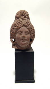 An Egyptian terracotta head of a woman: An Egyptian terracotta head of a woman, Ptolemaic, c. 3rd - 1st Century BC, her hair nicely styled into a coiled plait at the back of the head, her features attractive and ears with holes for