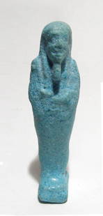 An Egyptian pale blue faience ushabti: An Egyptian pale blue faience ushabti, Late Period, c. 664 - 332 BC, mummiform on integral base, wearing tripartite headdress and false beard, arms folded across chest, hands holding a pick and hoe,