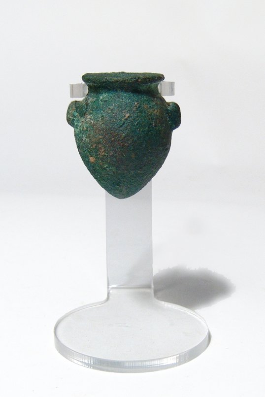An Egyptian bronze jar, Late Period: An Egyptian bronze jar, Late Period, c. 664 – 30 BC, well formed with pierced lug handle and a wide flat rim. 32 x 28mm. Custom lucite base. Ex-Hamedian Gallery, Jerusalem.