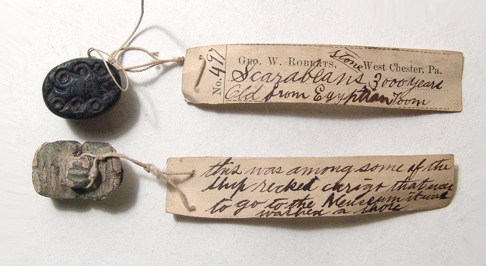 Pair of Egyptian scarabs with antique labels: A pair of Egyptian scarabs with antique labels. The first is a 2nd Intermediate example, c. 1750 – 1570 BC, in black serpentine, a corded pattern on the base, (18x13mm). The second a ‘button’ sc