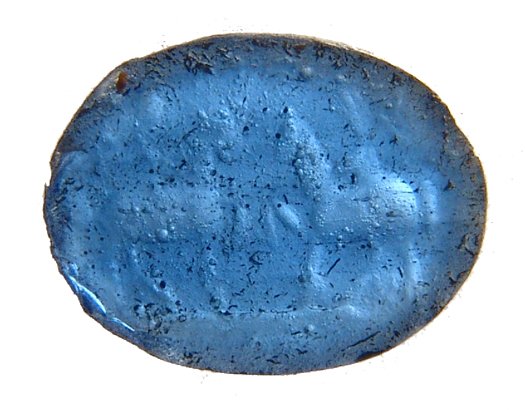 A Roman glass intaglio with the Dioscuri: A Roman glass intaglio with the Dioscuri, c. 1st Century AD, an attractive translucent blue ring stone featuring both on horseback facing one another. 12.5 x 9.5 mm. The Dioscuri (Castor and Pollux or