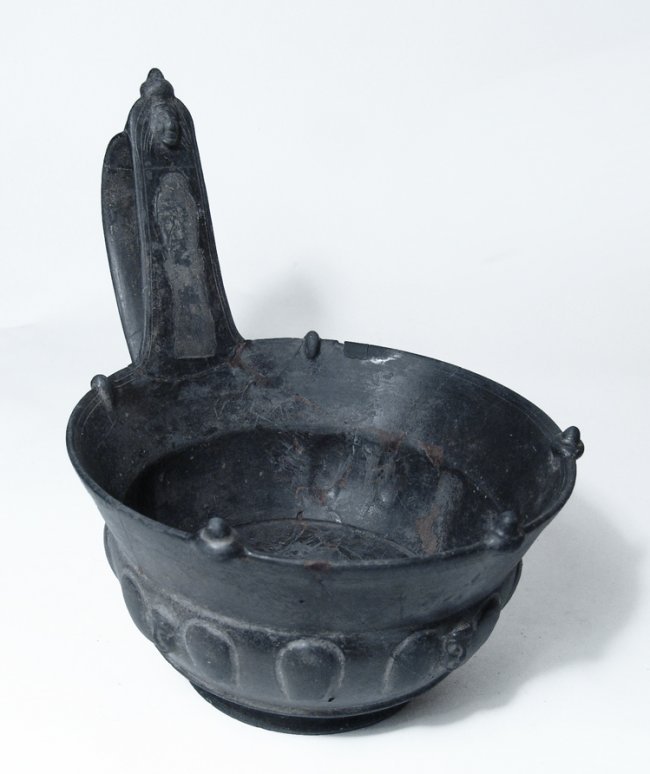 A choice Bucchero pesante Kyathos: A choice Bucchero pesante Kyathos, c. 560 - 540 BC, the bowl beautiful decorated with raised petals and three human faces in relief. The tall handle, which is flanked by two low projections on the rim