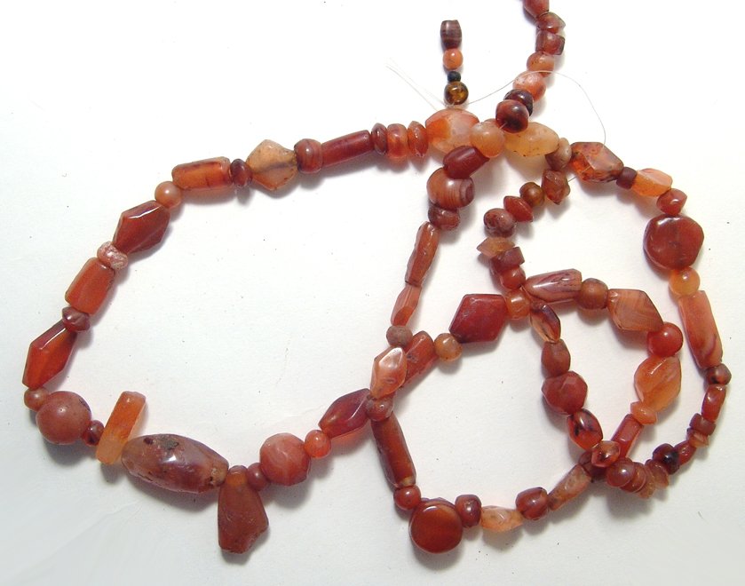A beautiful strand of carnelian beads, Holy Land: A beautiful strand of carnelian beads, Holy Land, c. 1st Millennium BC, in a variety of shapes and sizes, each hand cut and drilled, many retaining their original polish. L: 31 in (78.5 cm). Ex Los An