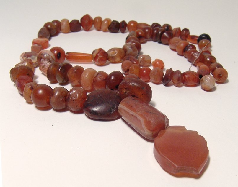 A strand of very nice carnelian beads, Holy Land: A strand of very nice carnelian beads, Holy Land, c. 1st Millennium BC, with central pendant. The beads are of various shapes and sizes, most translucent with vibrant color, each hand cut and drilled,