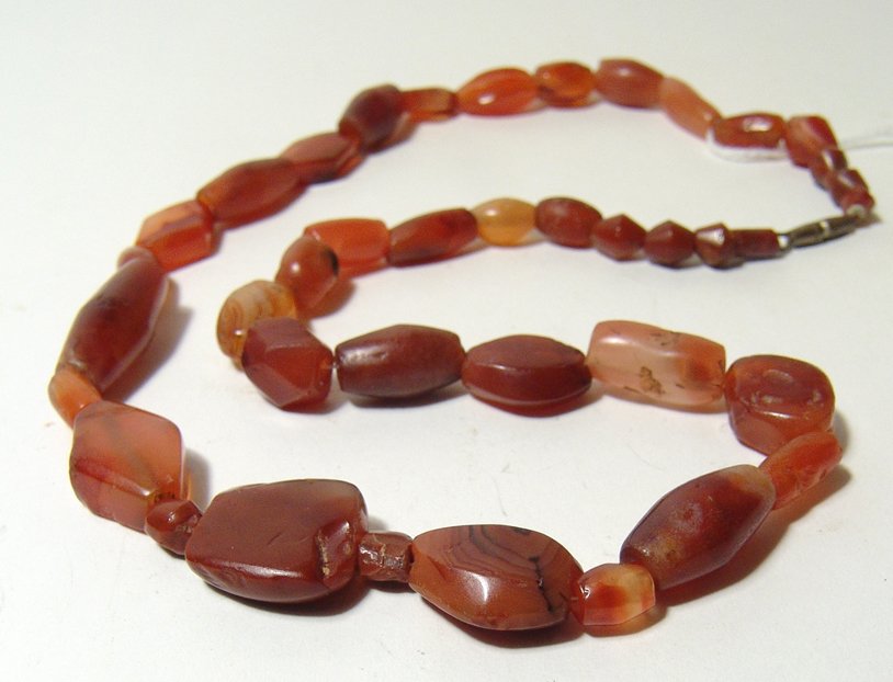 A necklace comprised of mixed carnelian beads: A necklace comprised of mixed carnelian beads, c. 1st Millennium BC/AD, with differing shapes including rounded examples and some with faceted sides, several with nice desert varnish. L: 18 3/5 in (47