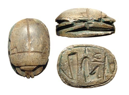 Egyptian steatite scarab. New Kingdom, Ramesside: An Egyptian brown steatite scarab New Kingdom, Ramesside, c. 1200 - 1075 BC, the body nicely carved with traces of green glaze and inscribed base. L: 3/5 in (1.6cm), W: 1/2 in (1.2cm). Holed lengthwis