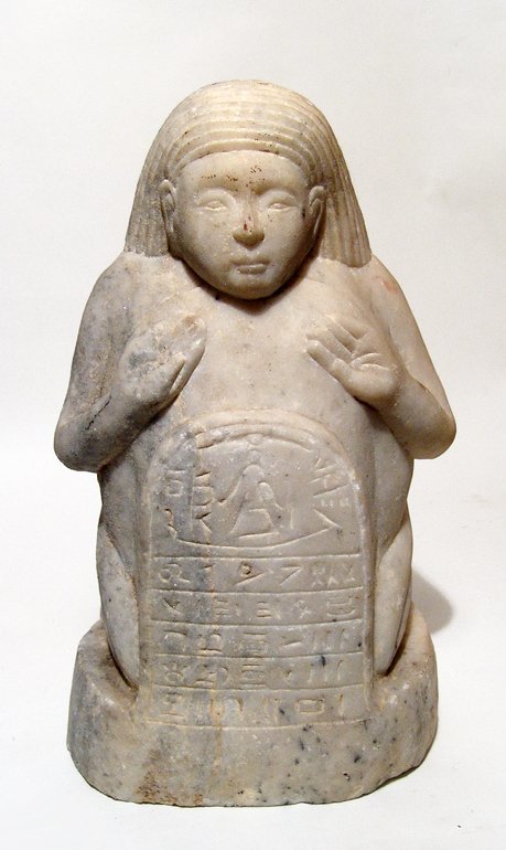 A Sabaean marble sculpture of a kneeling male: A Sabaean marble sculpture of a kneeling male, perhaps a dwarf, South Arabia, c. 2nd - 1st Century BC, in Egyptian style wearing striated wig, his hand on his chest above a stele which rests against h