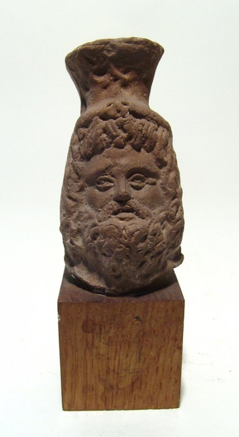 Romano-Egyptian terracotta head of Serapis: A Romano-Egyptian terracotta head of Serapis, c. 2nd - 3rd Century AD, heavily bearded and with long curly hair, wearing a modius decorated with olive branches on the front. H: 3 3/4 in (9.5 cm). Beau