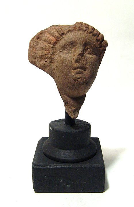 A Greek terracotta head of a lady: A Greek terracotta head of a lady, Egypt, c. 2nd – 1st Century BC, her features attractive and her hair styled in ridges beneath a large rolled diadem, the bottom of which is still visible. H: 2 1/5