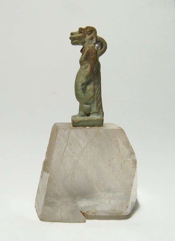 An Egyptian faience amulet of Taweret: An Egyptian faience amulet of Taweret mounted on a crystal base, Late Period, c. 664 – 30 BC, in classic form with head of Hippopotamus and pregnant belly, suspension loop at back of neck. The amule
