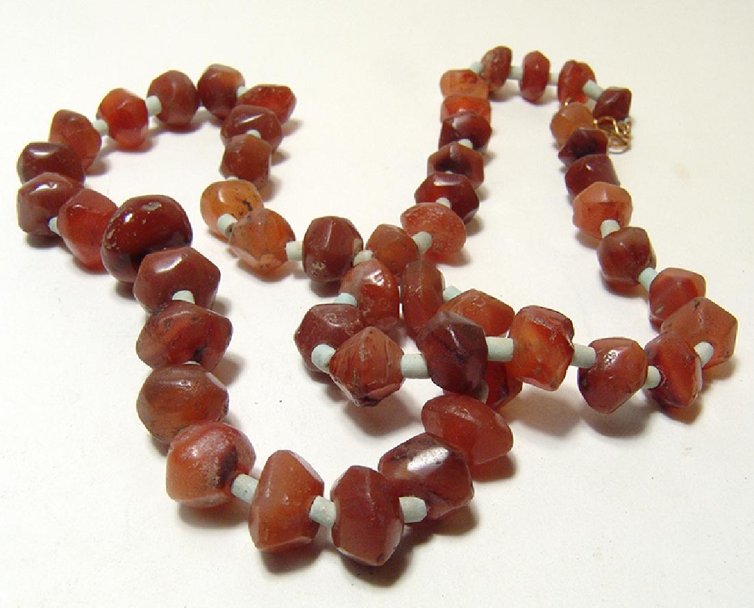A nice strand of Parthian faceted carnelian beads: A nice strand of Parthian faceted carnelian beads, c. 2nd – 1st Century BC, of varying shapes and interspersed with small pale blue faience tubular beads. L: 22 in (55.6 cm). Ex Colosseum Coin Excha