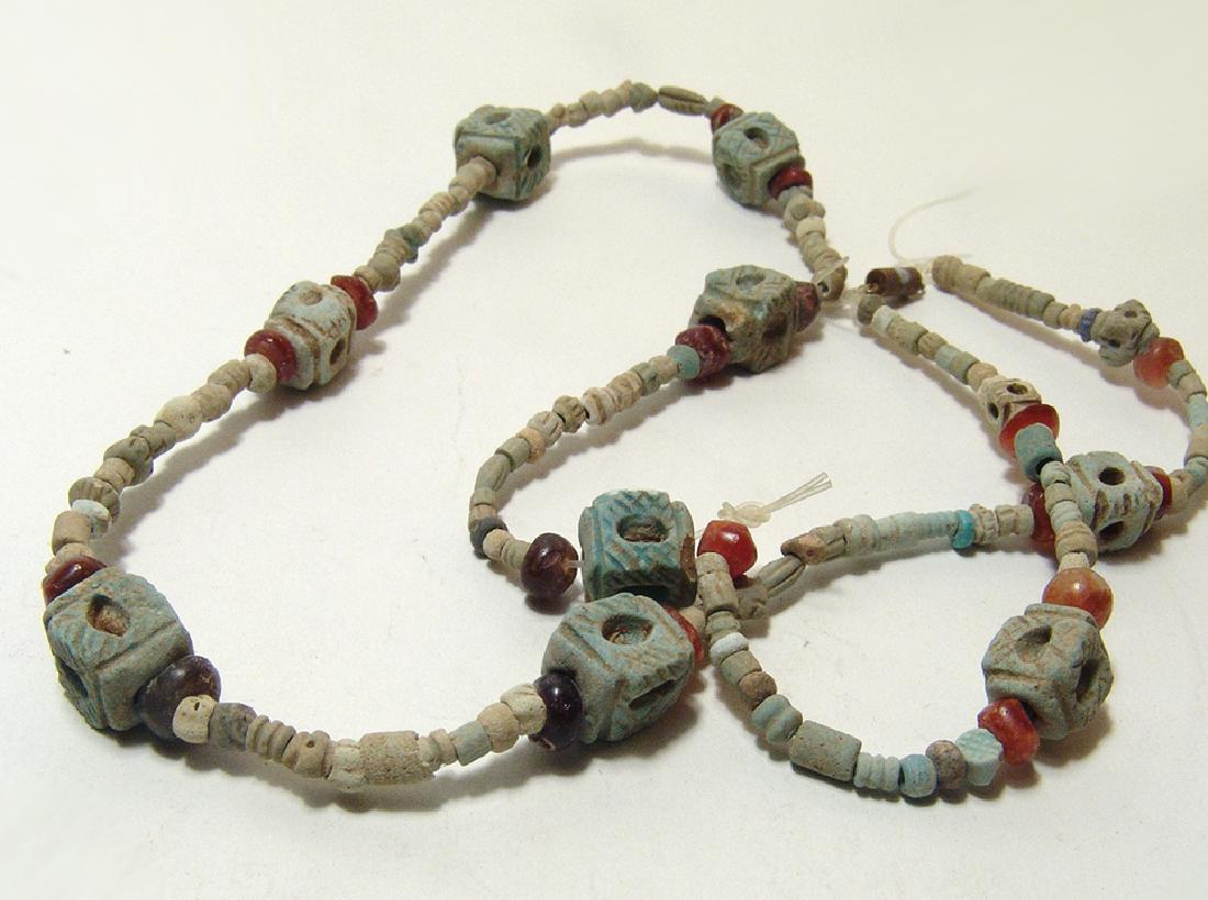 A strand of Parthian faience and carnelian beads: A strand of Parthian faience and carnelian beads, c. 3rd – 1st Century BC, the faience beads of varying sizes and strung with 9 rectangular faience beads decorated with holes and incised lines and i