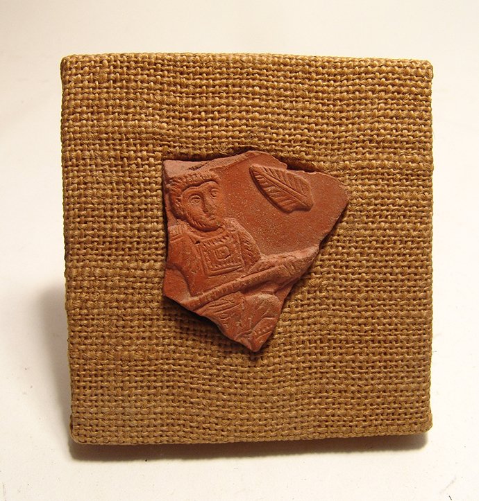 Roman terra sigillata fragment depicting a soldier: A Roman terra sigillata fragment depicting a soldier, North Africa, 4th – 5th Century AD, very nicely detailed, the man in military attire with closely cropped hair and holds a spear; a leaf in the 