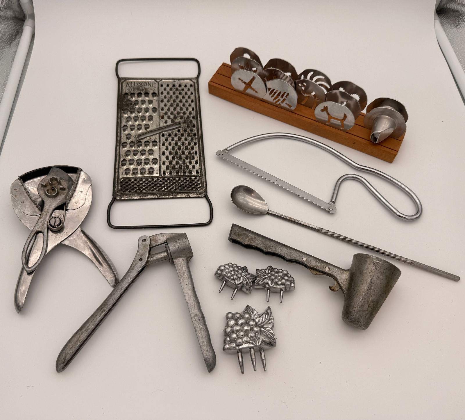 Lot of Vintage Kitchen and Bar Utensils, 1930s–1950s: Collection of vintage kitchenware including grater, garlic press, nutcracker, pastry cutters, bar tools, and serving accessories.