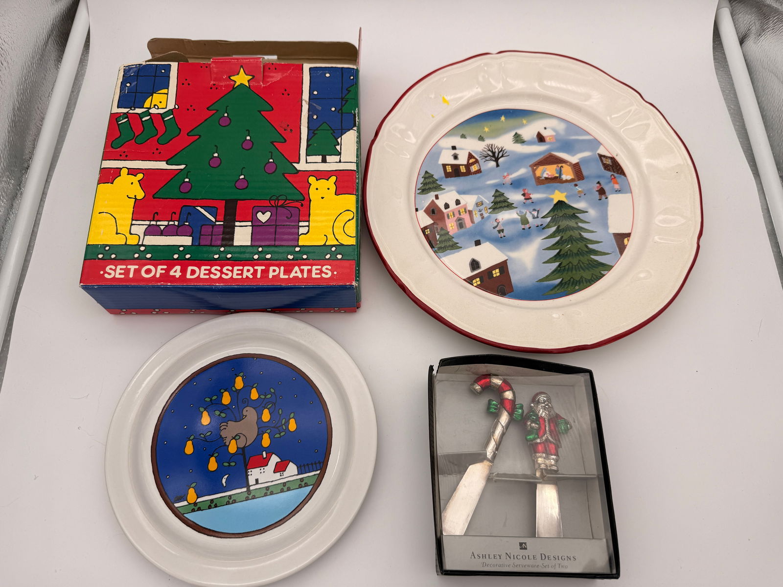 Vintage Christmas Serveware Lot incl. Houze, Nantucket & Ashley Nicole Designs: Lot of festive Christmas-themed tableware including 1985 Houze Japan “Partridge in a Pear Tree” glass plate, Nantucket “Home for Christmas” plate, boxed dessert plate set of four, and