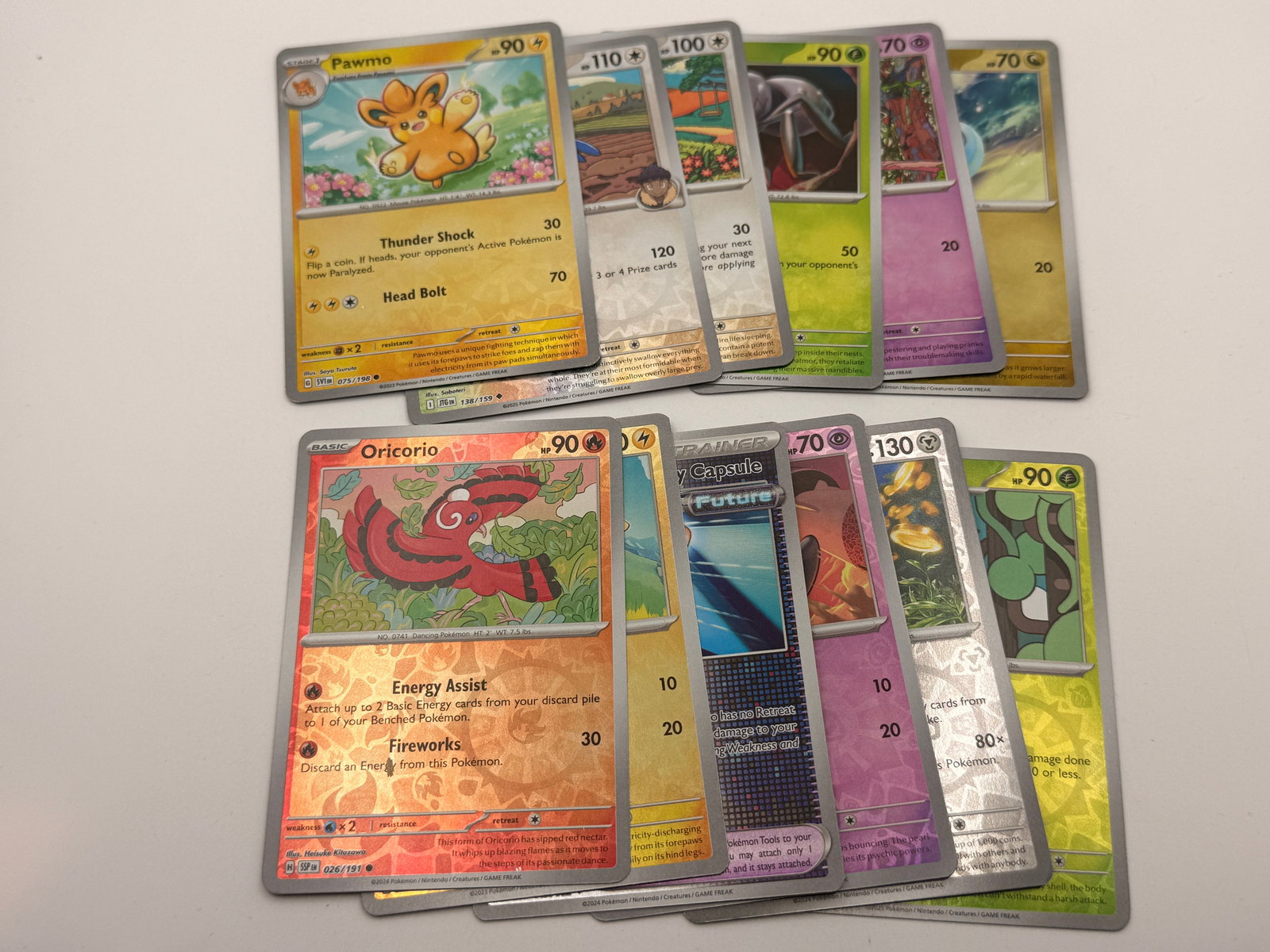 Lot of 12 Modern Pokémon Reverse Holo & Holo Cards: Group of twelve modern Pokémon TCG cards, consisting of assorted reverse holographic and standard holographic. Suitable for collectors or as a bulk enhancement lot.