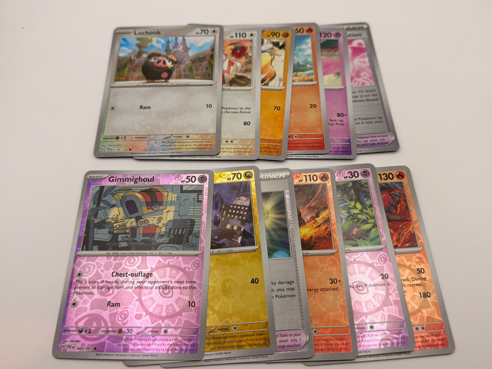Lot of 12 Modern Pokémon Reverse Holo & Holo Cards: Group of twelve modern Pokémon TCG cards, consisting of assorted reverse holographic and standard holographic. Suitable for collectors or as a bulk enhancement lot.