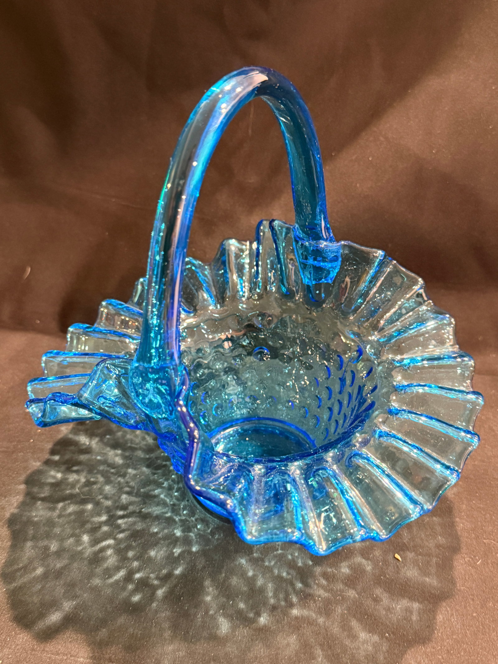 Blue Pressed Glass Basket with Handle: Blue pressed glass basket with ruffled rim, applied handle, and decorative textured interior. 7.25" x 6" x 6.75"