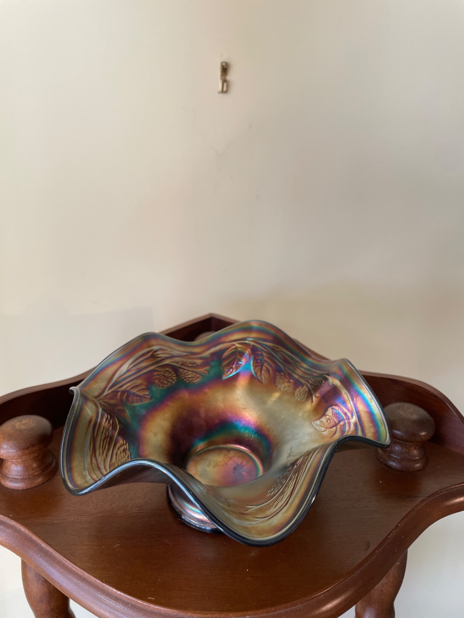 Iridescent Glass Bowl with Fluted Rim and Embossed Patterns: An iridescent glass bowl with a ruffled/fluted rim, measuring approximately 6-7 inches in diameter. Features embossed patterns likely of leaves and berries. The base has a polished flat foot,