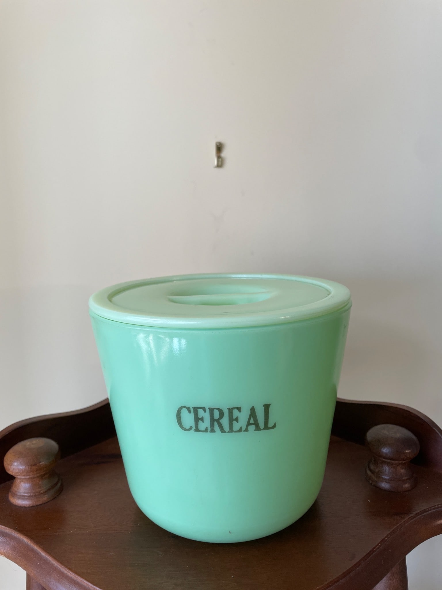 Jadeite Green Glass Cereal Canister With Lid: A light green glass cereal canister with an embossed 'CEREAL' label on the exterior. Includes a matching lid with an integrated handle. The canister measures approximately 5 inches in height, as
