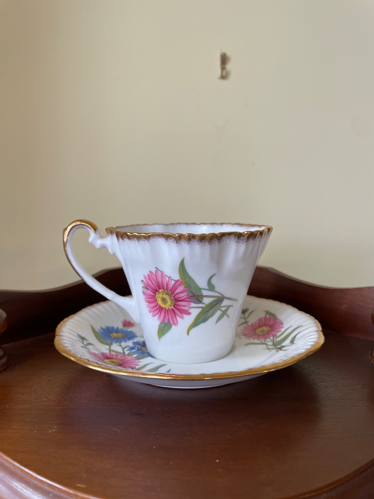 Salisbury Bone China Teacup and Saucer Set with Floral Motif: Salisbury Bone China teacup and saucer set made in England. Features a floral motif with pink and blue flowers and gold trimming on the rims and handle. The underside of the teacup is marked with the