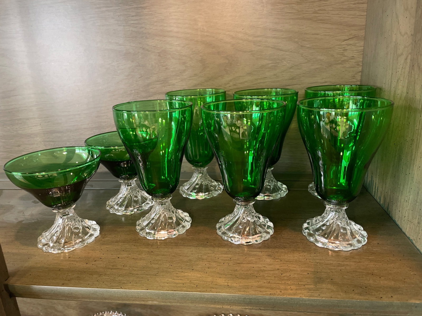 9 Green Glass Stemmed Goblets and Dessert Glasses with Clear Bases: 9 glassware pieces, including 6 stemmed goblets and 3 dessert glasses. Each piece features a green bowl and a clear molded base with scalloped detailing. Material appears to be glass. Manufacturer,