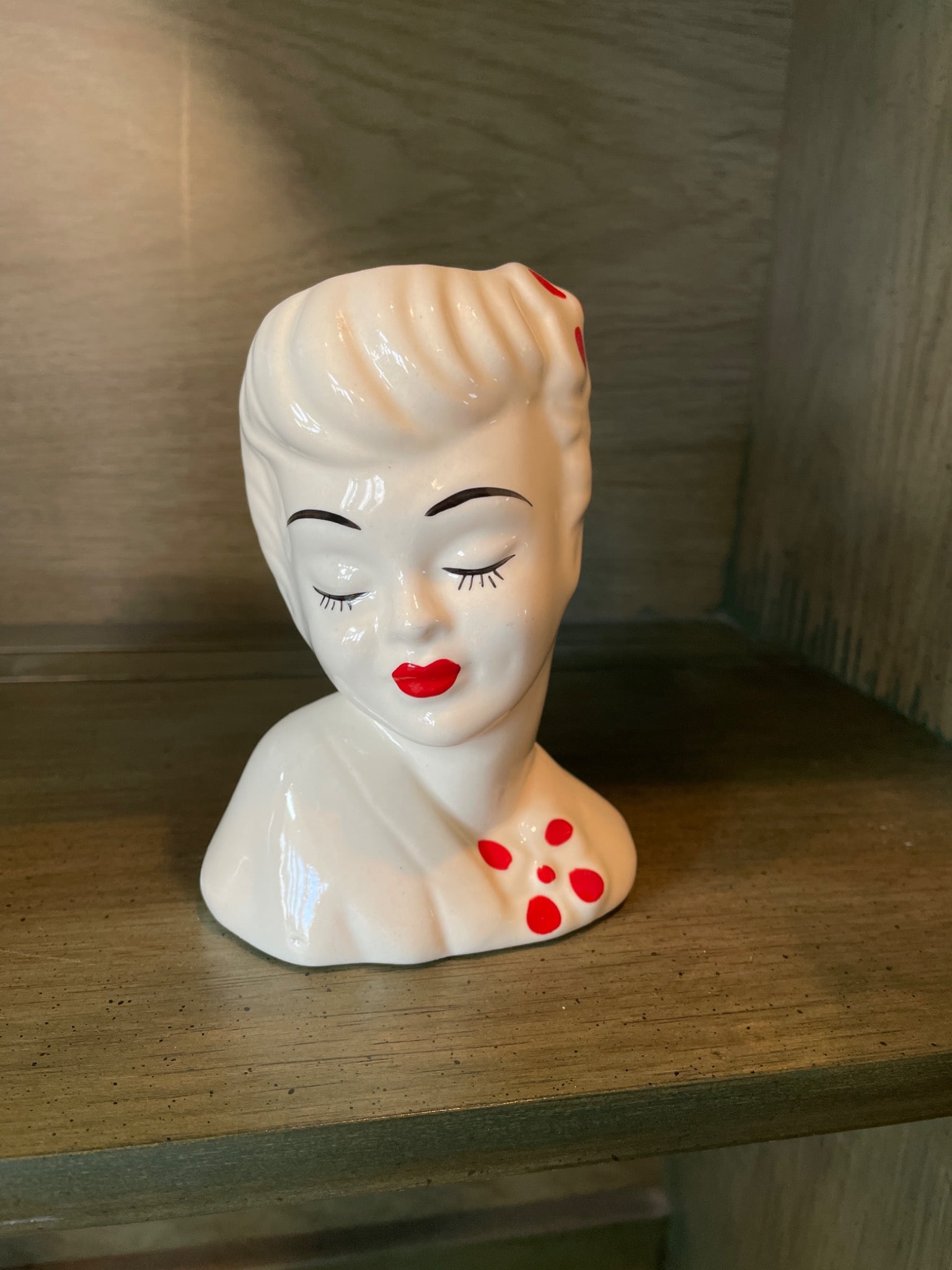 Ceramic Head Vase in Lady Design with Red Polka Dot Accents: This ceramic head vase features a lady design with hand-painted red polka dot accents. The vase includes an opening at the top for use as a planter or display piece. Measuring approximately 5 inches i