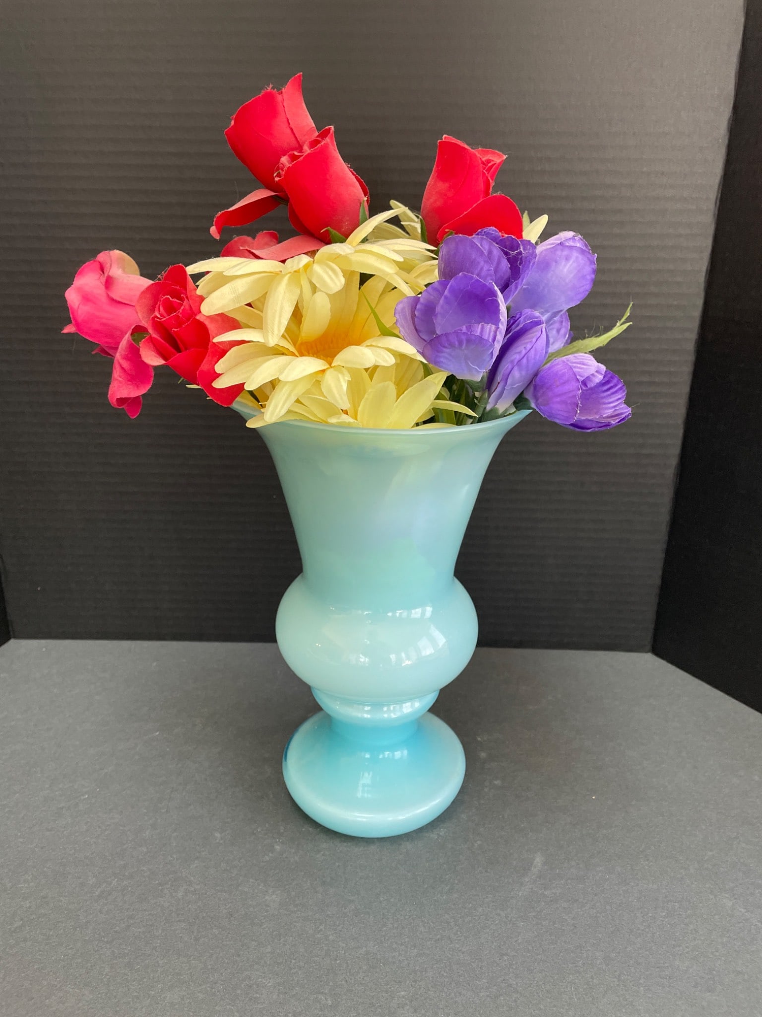 Glass Vase With Faux Flowers, Sky Blue, Approx. 10 Inches Tall: This lot features a glass vase with a sky-blue finish and a curved, dual-section design. It measures approximately 10 inches in height, as shown in the image with a ruler for reference. Includes a set