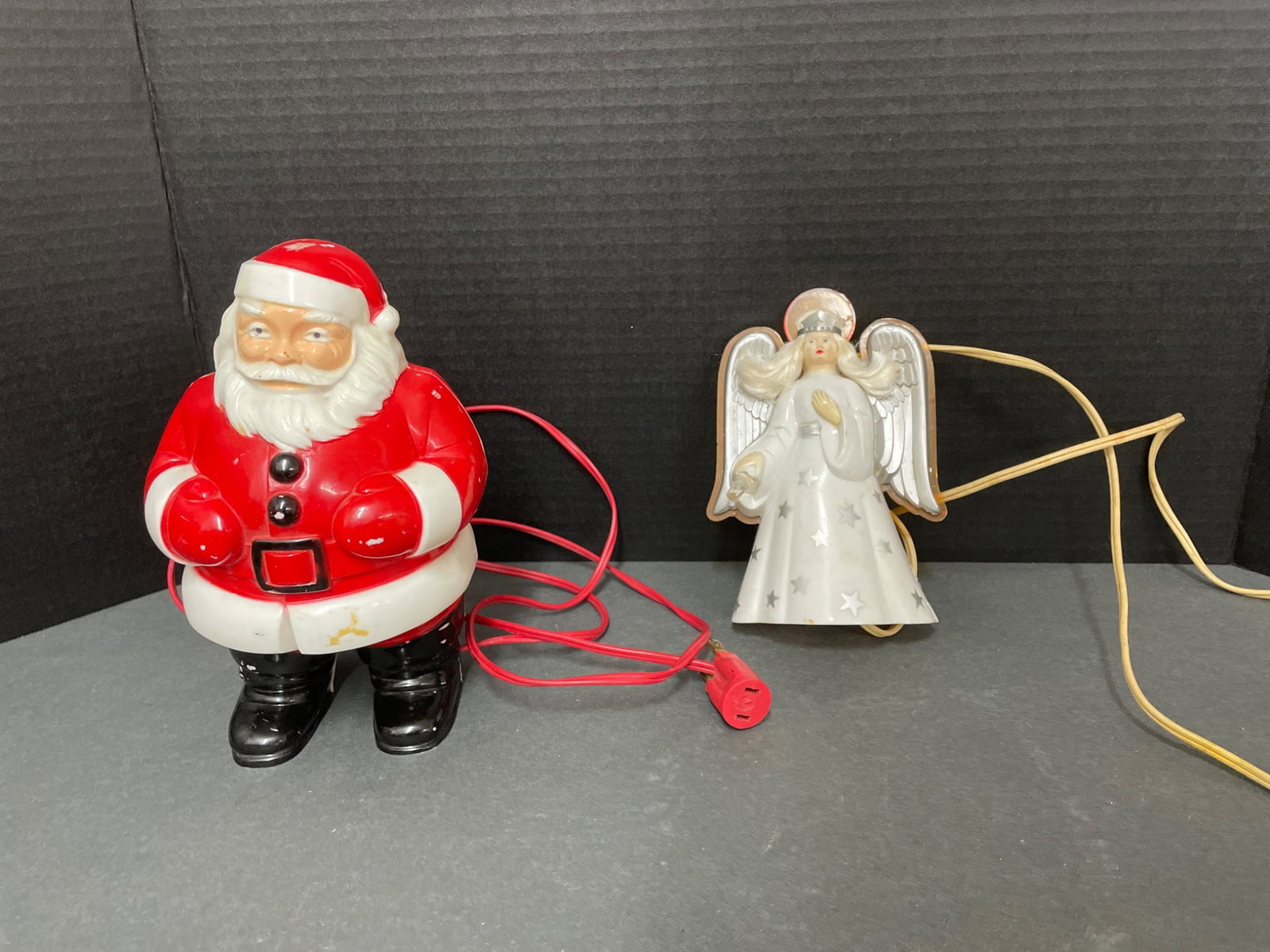 Electrified Santa Claus and Angel Figurines With Tested Functionality: This lot includes two electrified figurines: a Santa Claus with red and black coloration and an angel with a white and yellow design. The angel is confirmed to be working when tested, while the Santa